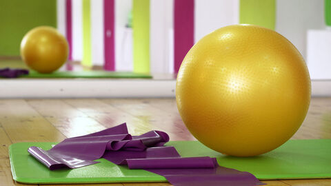 Fitness (Symbolbild) Medizinball, Yogamatte und Band liegen vor einem Spiegel in einem Trainingsraum.